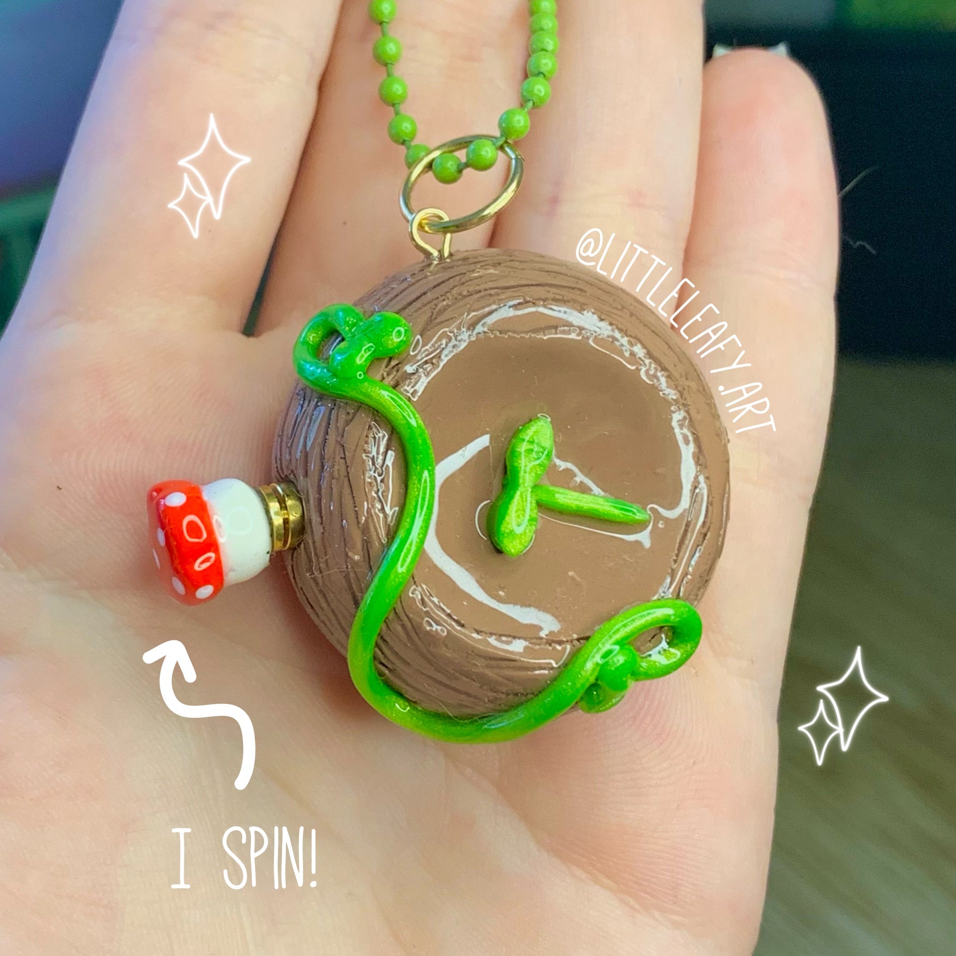 Hand holding a small wooden toy with green beads and a mushroom figure, labeled 'I Spin!'.