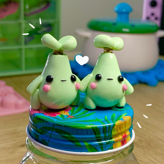 Two green cartoon-like figures on a colorful lid of a jar with a playful background.