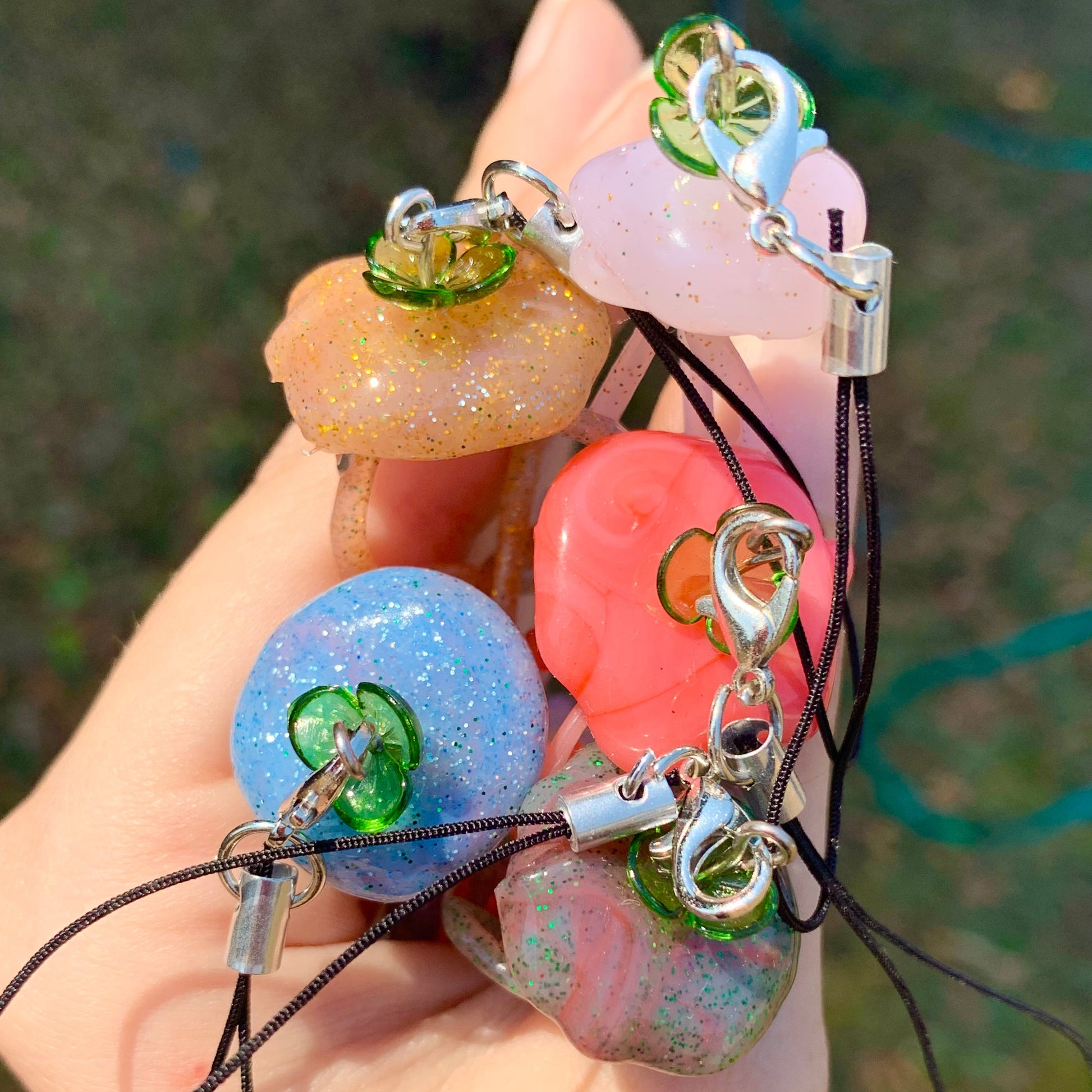 Colorful phone charm with glittery stones held by a hand against a blurred background