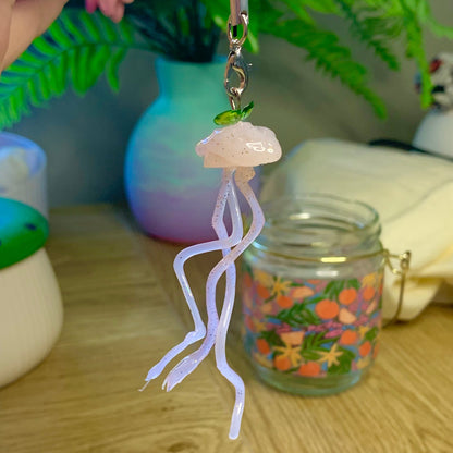 Decorative jellyfish charm hanging from a string on a wooden surface with a blurred background.