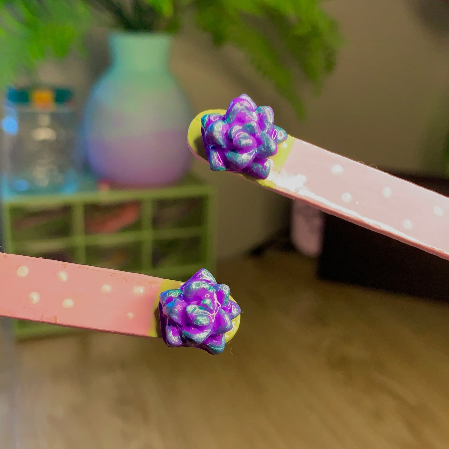 Pink sticks with purple flower-like ends on a wooden floor with blurred background