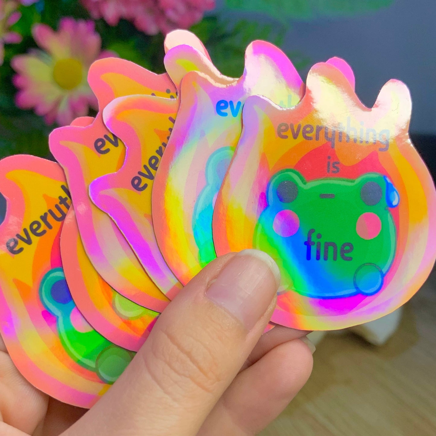 Colorful 'everything is fine' stickers held by a hand with a blurred background