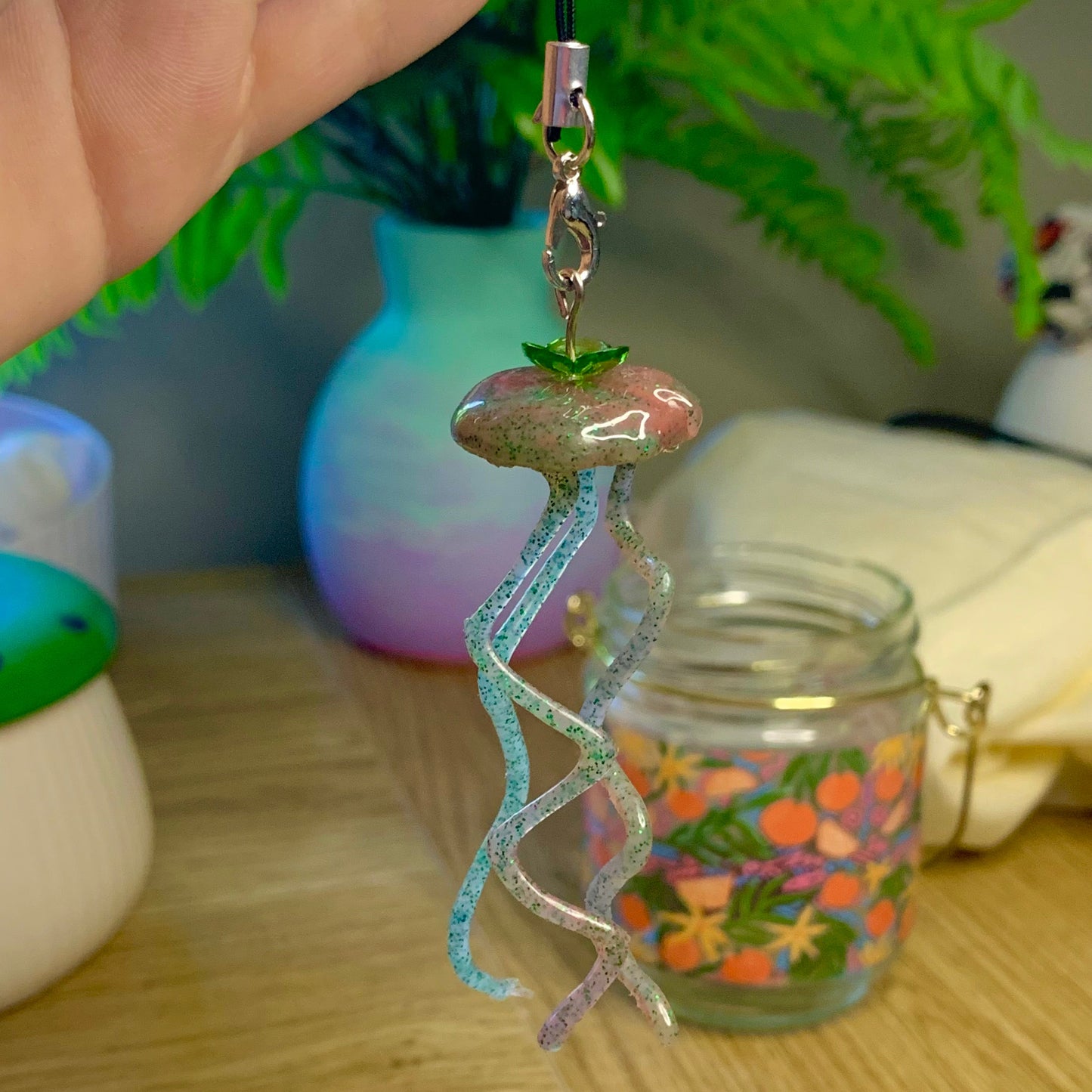 Decorative keychain with a colorful design held by a hand on a wooden surface.